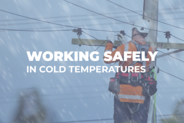 Utility worker wearing high-visibility safety gear repairs power lines during snowy weather, with text reading “Working Safely in Cold Temperatures.”
