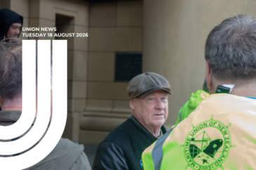 Union News banner for Tuesday 18 August 2026. A group of people stand outside a stone building in light rain; one wears a hi-vis vest with the Maritime Union of New Zealand logo. A white half U graphic sits over the left of the image.