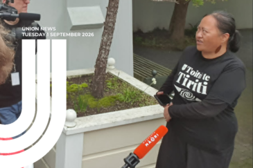 A woman in a black Toitū te Tiriti T-shirt speaks to media outside a building, holding a phone. A Whakaata Māori microphone is held up in front of her and a camera operator films from the left. Overlaid text reads 'Union News, Tuesday 1 September 2026'