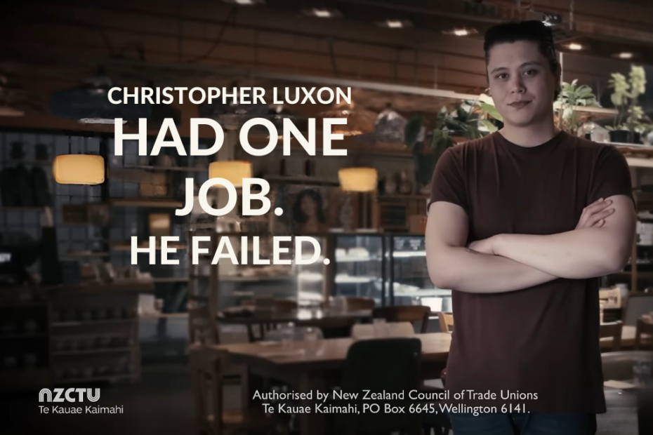 Still from an NZCTU campaign advertisement. Large white text over a dimly lit café interior reads “Christopher Luxon had one job. He failed.” On the right, a young man in a dark red T-shirt stands with his arms folded, looking at the camera. The NZCTU Te Kauae Kaimahi logo sits in the bottom left, with an authorisation statement.