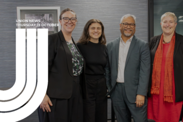 Graphic for Union News: Thursday 15 October. Colour photo of four people standing together indoors and smiling at the camera – from left, Melissa Ansell-Bridges, Chlöe Swarbrick, Teanau Tuiono, and Sandra Grey – with a framed picture on the textured grey wall behind them. White curved lines overlay the left side of the image.