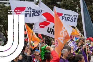 Graphic for Union News: Monday 19 October 2026. Colour photo of a large crowd at an outdoor rally, with white Workers First Union flags, orange PSA flags and purple flags flying above them. A placard reads “Pay equity now”, and one person waves green tinsel pom-poms. Trees and city buildings are in the background. White curved lines overlay the left side of the image.