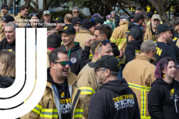 Graphic for Union News: Tuesday 27 October 2026. Colour photo of a large group of firefighters gathered outdoors, many in tan jackets with reflective stripes and black NZPFU caps and hoodies reading “Together Stronger – Kaha Tapatahi”. Several are talking and laughing. White curved lines overlay the left side of the image.